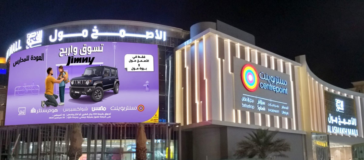 Night view of Al Asmakh Mall with a large billboard promoting the back-to-school campaign to win a Suzuki Jimny.