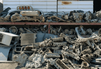 Pile of used car parts stacked in an industrial workshop, reflecting concerns over high prices and lack of warranties in Qatar."
